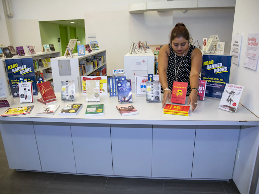 Photo of a person straightening out a pile of books on a table display