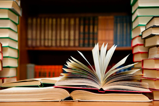 A photo of a library, books piled on shelves, some books sitting open atop one another