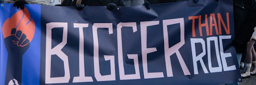 Poster held up by a group of people, stating 