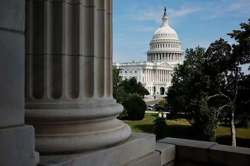A photo of the U.S. Capitol from behind a column in a nearby legislative building.