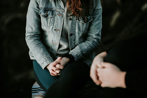 Photo of a person sitting in a waiting room, hands clasped in their lap