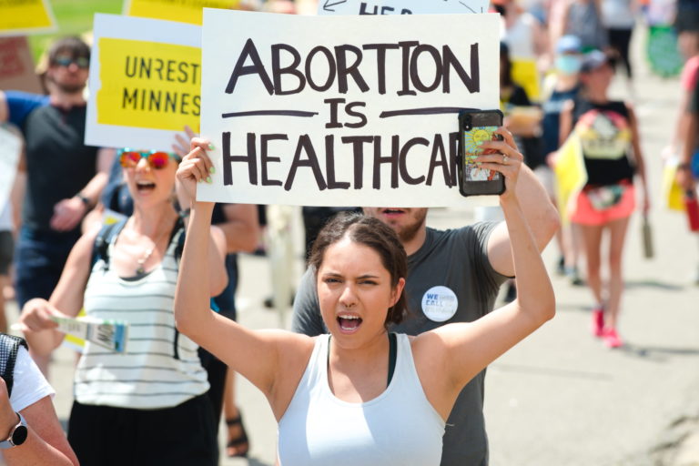 Photo of protester holding up a sign which says 
