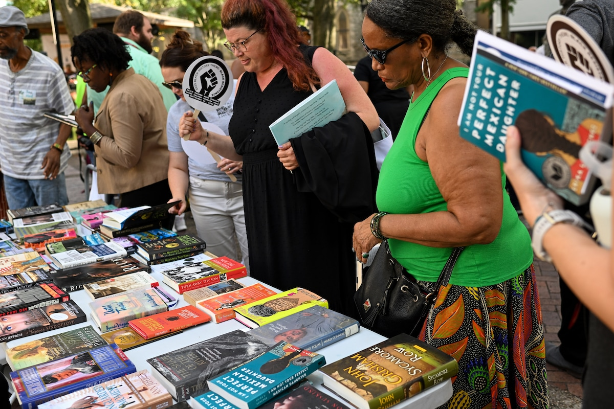 Photo of a group of people looking at a table filled with books